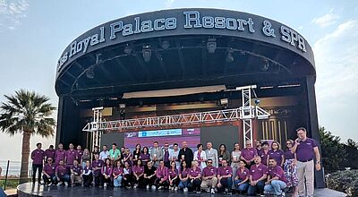 Bei der Premiere des Event-Formats „Club oft the Best“ zeichnete Bentour die besten Reisebüro-Partner aus Auf der Bühne stehen zahlreiche Bentour-Mitarbeiter, in lila gekleidet, zusammen mit Reisebüro-Partnern, die einen Preis gewonnen haben, im Hintergrund blauer Himmel und Palmen.